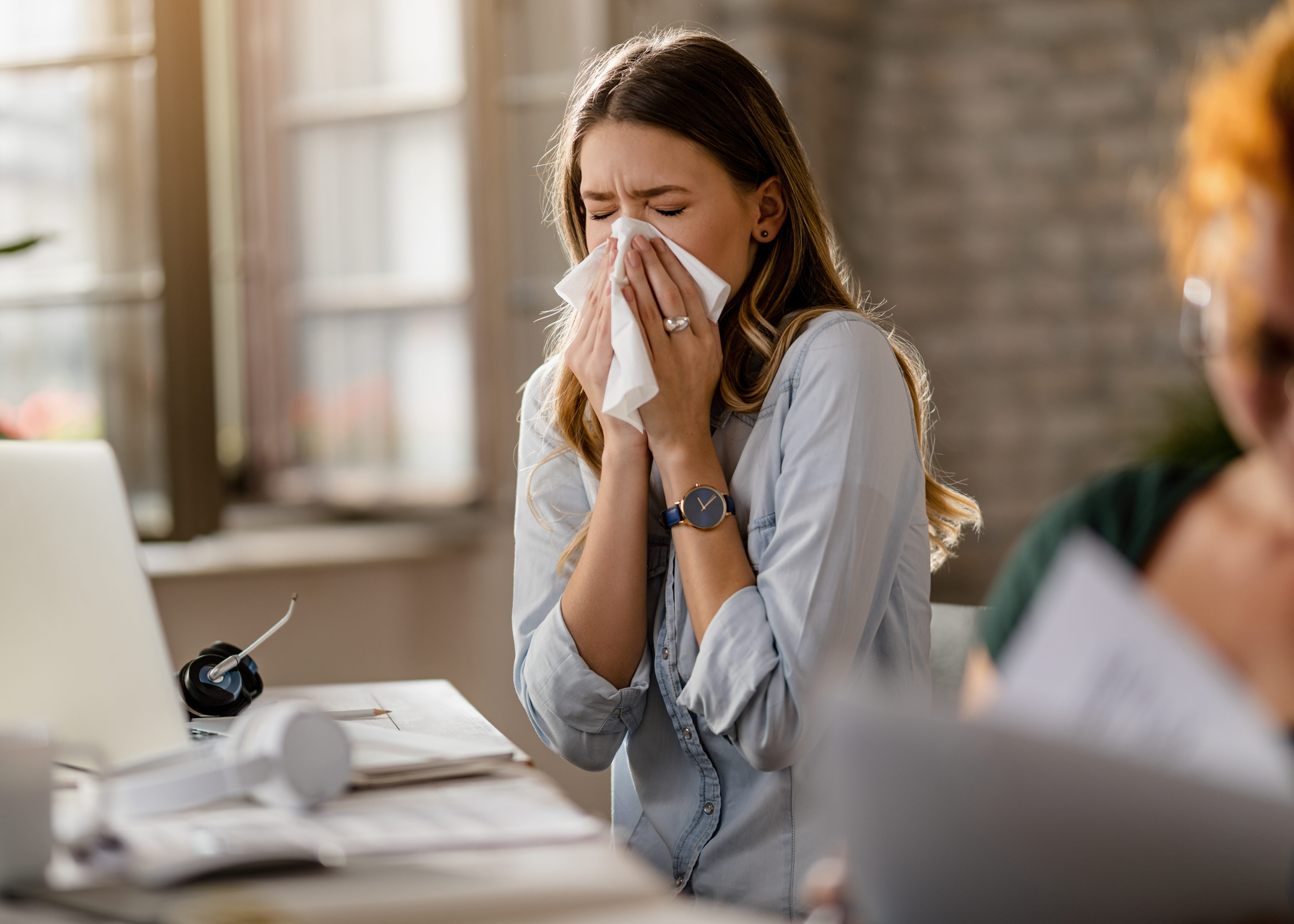 Jeune femme d’affaires utilisant un mouchoir en éternuant au bureau