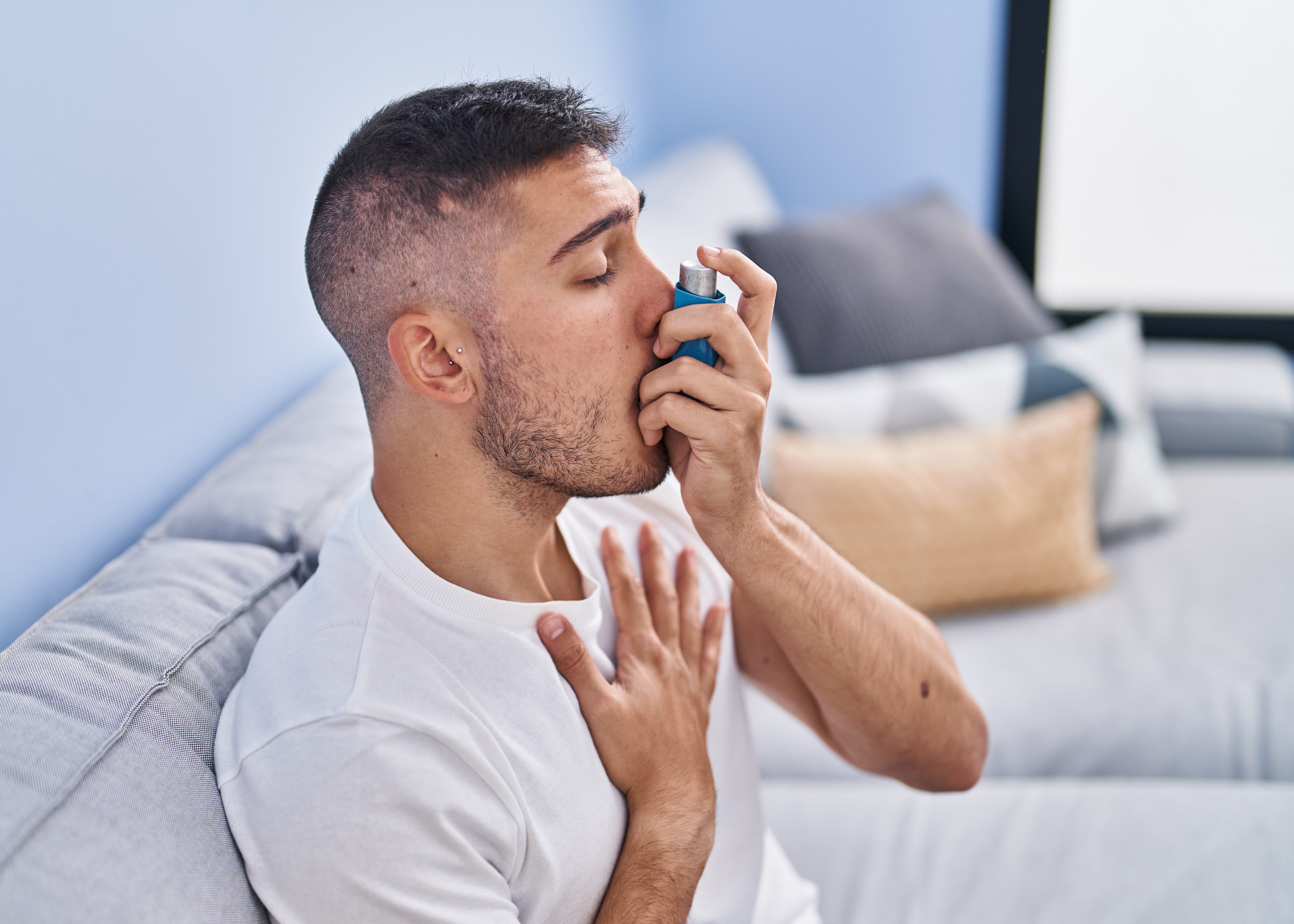 Personne avec asthme utilisant un traitement inhalé assis sur le canapé